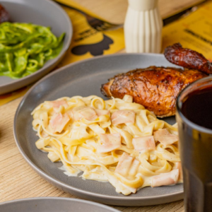 Savory Peruvian-style chicken served with creamy pasta and fresh sides in Tacna, Perú.