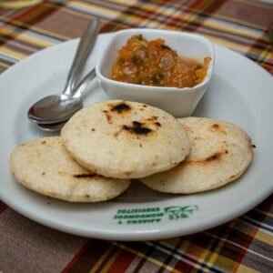 a white plate topped with food next to a bowl of salsa